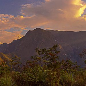 Montaña atardecer sol nubes cielo azul. Un atardecer con sol.