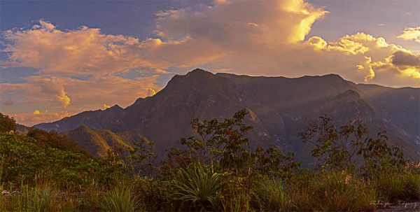 Montaña atardecer sol nubes cielo azul. Un atardecer con sol.