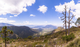 paisaje de monta&ntilde;a, rocas, arboles, cielo azul, nubes blancas.